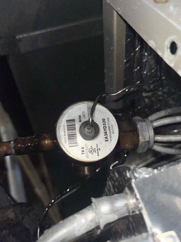 Responded to no cooling complaint on residential air conditioning unit. Upon inspection, found heavily corroded copper service valve and refrigerant fitting at evaporator coil with visible oxidation and green patina buildup. Evaporator coil showed signs of moisture accumulation and dirt buildup on aluminum fins. Documented equipment condition including model EMBD520 and compromised refrigerant connections that likely contributed to system's inability to produce cold air.
