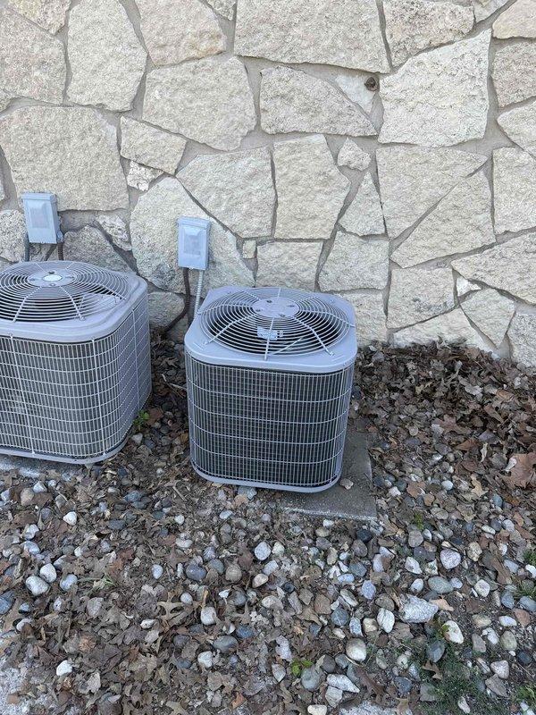 Completed installation of customer-supplied air conditioning system and air handler unit in end closet location. The new black air handler was mounted vertically in the utility closet with proper ductwork connections, condensate pan, and filtration system installed. Exterior condenser units were positioned on gravel pad against stone wall with appropriate clearances and electrical disconnects mounted. Removed and transported old HVAC equipment to maintenance office for disposal.