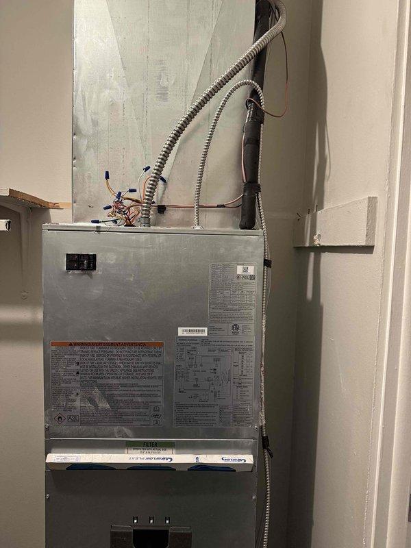 Removed and replaced 1.5 ton R22 ceiling-mounted fan coil and air conditioning system with new Carrier equipment in bedroom closet installation. Installed Carrier FMA5X2400AL 1.5 ton wall-mounted fan coil with 8kW electric strip heat and Carrier GA4SAN51800N 1.5 ton 14 SEER single-stage air conditioner utilizing R454B refrigerant. Cut open ceiling and wall to access existing ductwork, reconnected to existing supply and return ducts, and tied into existing condensation drain line. Extended refrigerant line set by 25 feet to connect to existing lines at end of hall, flushed and reused existing line set to maintain system integrity. Installed Honeywell T6 programmable thermostat, new PVC equipment pad for outdoor condenser, electrical disconnect with whip for code compliance. Reconnected to existing electrical power supply, performed system startup procedures, evacuated and charged unit to manufacturer specifications. Verified proper airflow, refrigerant pressures, and heating operation. 