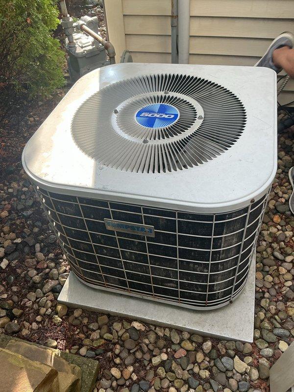 Conducted comprehensive assessment of non-operational air conditioning system and existing furnace for complete HVAC replacement estimate. Evaluated outdoor condenser unit with blue-logo branding positioned on concrete pad with proper drainage and clearances. Inspected garage-installed furnace, documenting internal components including copper refrigerant lines, gas piping, and mechanical connections. Measured existing equipment dimensions and clearances to determine replacement specifications. Photographed current system configuration, ductwork connections, and installation conditions to provide accurate replacement proposal for both heating and cooling equipment.