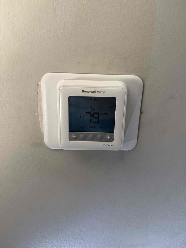 Removed and replaced existing 1.5 ton R22 ceiling-mounted fan coil and air conditioning system with new Carrier equipment in bedroom closet location. Installed Carrier FMA5X2400AL 1.5 ton wall-mounted fan coil with 8 kW electric strip heat and Carrier GA4SAN51800N 1.5 ton 14 SEER single-stage air conditioner utilizing R454B refrigerant. Cut and exposed ceiling and wall sections to access existing ductwork for proper reconnection to new air handler unit. Added 25' line set section to existing refrigerant lines running to end of hallway, flushed and reused existing line set to maintain system integrity. Reconnected all existing ductwork in ceiling, condensate drain line, and electrical power supply to new equipment. Installed Honeywell T6 programmable thermostat, PVC equipment pad for outdoor condenser unit, and electrical disconnect with whip for code compliance. Performed complete system startup, evacuated refrigerant lines, and charged unit to manufacturer specifications for optimal p