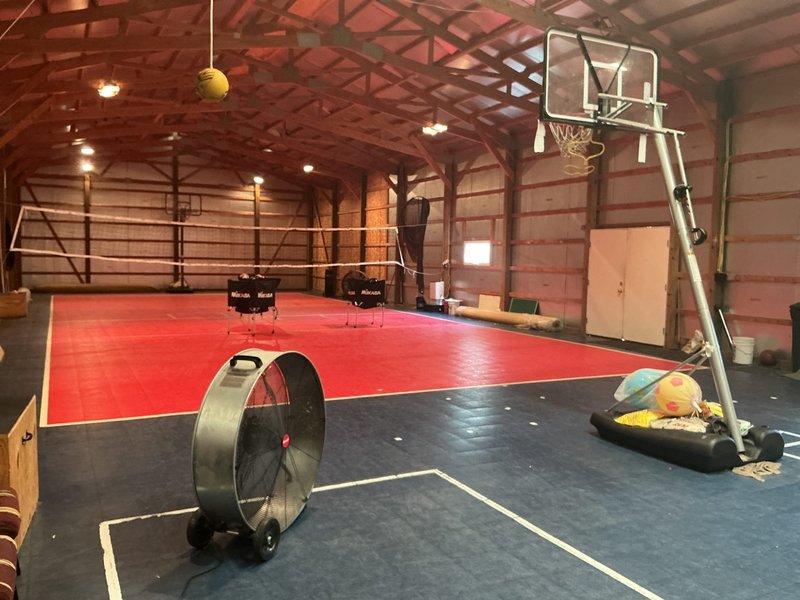 Conducted on-site evaluation for mini-split system installation in a 40' x 90' outbuilding converted to an indoor sports facility with no existing ductwork. Assessed the structure, which features exposed wooden beam construction with vaulted ceilings, multiple basketball courts, and volleyball playing areas with foam mat flooring. Documented facility layout and dimensions to determine optimal mini-split placement for heating and cooling the 3,600 square foot multipurpose athletic space, taking into account the high ceiling clearances, open floor plan, and recreational equipment positioning for proper air distribution throughout the building.
