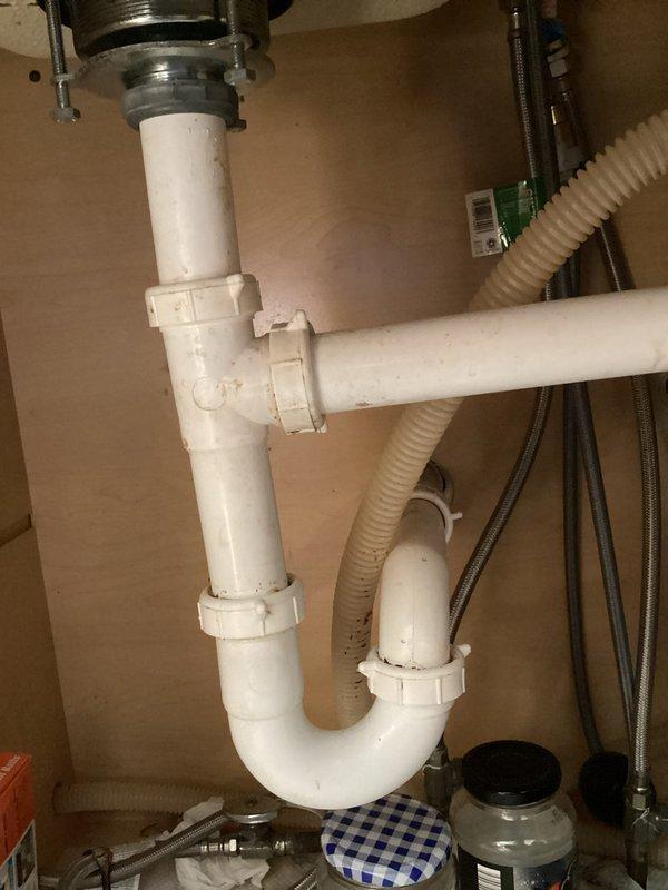 # Plumbing Maintenance Inspection Completed

Performed comprehensive plumbing maintenance inspection at installation site. Inspected and documented washing machine water supply connections through ceiling access panel, verifying proper installation of braided stainless steel flex lines with color-coded hot and cold fittings. Examined under-sink plumbing assembly including PVC P-trap configuration, garbage disposal mounting, and dishwasher drain connection. Verified all supply lines, drain components, and connections are secure and functioning properly with no visible leaks or defects detected.
