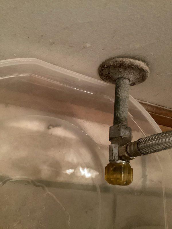 Responded to service call for leaking shut-off valve and continuously running toilet. Upon inspection, identified active leak at the connection point between the toilet supply shut-off valve and the wall supply line, occurring before the pipe enters the wall. Valve assembly showed significant accumulation of debris and age-related wear. Additionally diagnosed toilet fill valve malfunction causing continuous water flow into tank. Documented existing conditions with photographs showing corroded valve hardware, braided supply line connections, and overall plumbing configuration. Temporary containment vessel was in place beneath leak point upon arrival to prevent water damage.