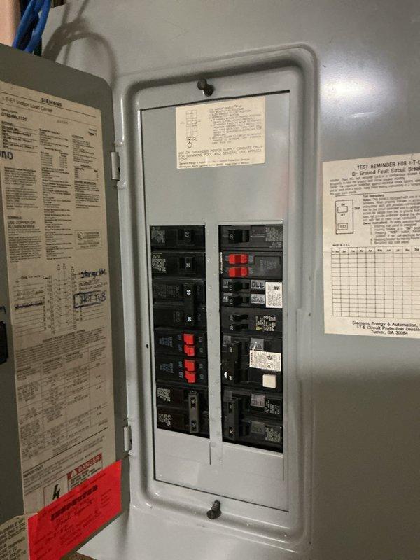 Responded to service call for irrigation system electrical reconnection and additional electrical concerns. Inspected main electrical panel and assessed circuit breaker configuration for irrigation system requirements. Evaluated ceiling cavity wiring where multiple conductor runs were exposed, including yellow Romex, white, orange, blue, and black wiring routed through wooden framing members with gray junction boxes. Documented existing electrical infrastructure conditions via photographs for customer records and future reference.