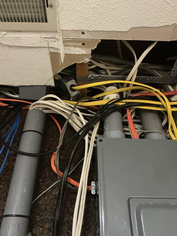 Responded to service call for irrigation system electrical reconnection and additional electrical concerns. Inspected main electrical panel and assessed circuit breaker configuration for irrigation system requirements. Evaluated ceiling cavity wiring where multiple conductor runs were exposed, including yellow Romex, white, orange, blue, and black wiring routed through wooden framing members with gray junction boxes. Documented existing electrical infrastructure conditions via photographs for customer records and future reference.