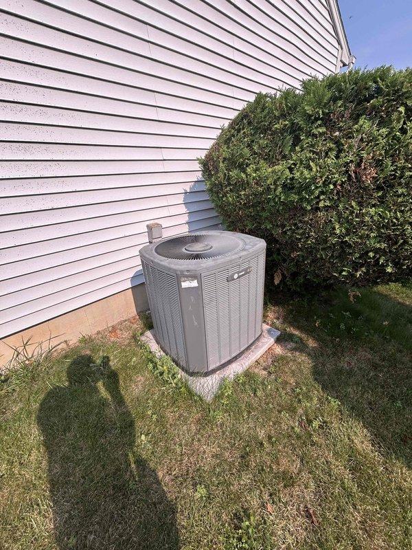 Tech lead Alex conducted a comprehensive HVAC system evaluation for equipment replacement. Assessment included inspection of the existing outdoor air conditioning condenser unit installed on a concrete pad against the building's exterior, as well as the indoor furnace system located in the basement mechanical room alongside the water heater. Detailed photographic documentation was captured of both the exterior condensing unit with its current installation configuration and the interior furnace with associated ductwork and PVC venting systems to support replacement specifications and planning.