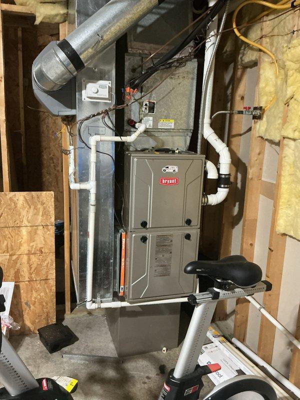 Responded to no cooling complaint on 20-year-old residential air conditioning system that had experienced freeze-up and was not maintaining temperature. Performed comprehensive evaluation of existing Bryant furnace located in unfinished basement and outdoor condensing unit positioned on gravel pad against building exterior. Assessed refrigerant lines, PVC drainage and venting components, ductwork configuration, and overall system condition to provide complete replacement estimate for aging HVAC equipment that was no longer keeping up with cooling demands.