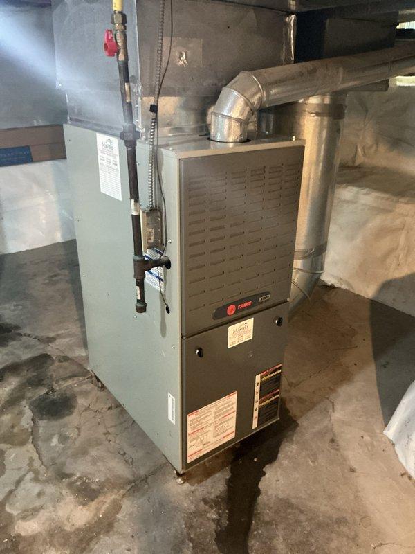 Conducted on-site assessment for air conditioning system installation at residential property with existing Trane furnace but no previous AC system. Evaluated current HVAC infrastructure including furnace unit, ductwork configuration, and basement utility space layout to determine appropriate AC unit sizing and installation requirements. Documented existing equipment conditions, noting moisture concerns on concrete flooring near furnace base and available space for outdoor condenser placement. Assessed electrical panel capacity and existing duct system compatibility for seamless AC integration with current forced-air heating system. Provided comprehensive estimate for complete air conditioning unit installation including condensing unit, evaporator coil, refrigerant lines, electrical connections, and necessary modifications to existing ductwork to accommodate cooling distribution throughout home.