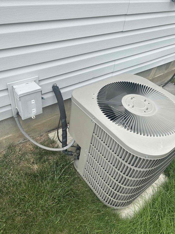 # HVAC System Replacement Estimate

Conducted comprehensive evaluation of residential HVAC system with all equipment approximately 24 years old. Assessed outdoor air conditioning unit, indoor furnace system, and water heater for replacement recommendations.

## Equipment Assessed

**Outdoor Unit:**
Inspected existing beige/tan cylindrical condenser unit with top-mounted fan assembly positioned on exterior pad. Evaluated electrical disconnect box, conduit routing, and refrigerant line connections. Unit mounted on level surface against building exterior with proper clearances maintained.

**Indoor Equipment:**
Examined Armstrong Air furnace installation in mechanical room with integrated blower assembly. Assessed white PVC exhaust/intake ventilation piping configuration extending from furnace cabinet. Evaluated copper refrigerant line routing along wall and electrical connections to system components. Reviewed water heater condition positioned adjacent to HVAC equipment.

## System Evalu