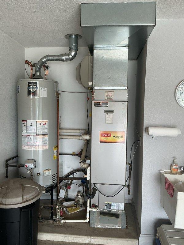 Completed on-site assessment for HVAC system replacement at residential property. Evaluated existing Bryant Plus 90 furnace and cylindrical outdoor air conditioning condenser unit for replacement recommendations. Documented current equipment specifications, installation configuration, utility connections, and mechanical room layout. Photographed indoor furnace installation including ductwork connections, gas piping, and proximity to water heater, as well as exterior condenser unit with refrigerant lines, electrical disconnect, and gravel pad mounting. Provided comprehensive replacement estimate for new heating and cooling system based on current equipment capacity and customer requirements.
