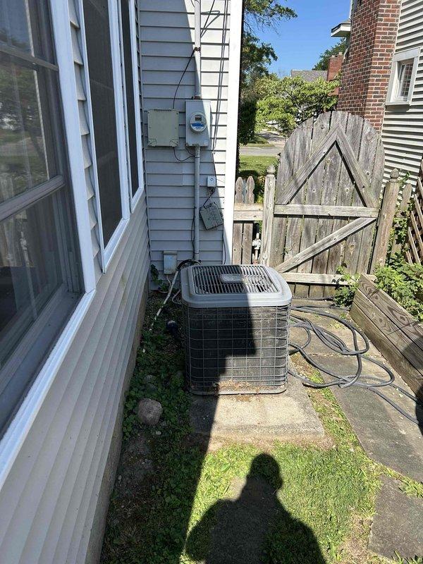 Responded to service call for frozen HVAC system at residential property. Upon arrival, assessed outdoor condenser unit positioned on concrete pad along side yard with gray vinyl siding. System evaluation revealed freezing condition requiring complete system replacement estimate. Provided comprehensive quote for new equipment installation while customer obtained competitive bids from multiple contractors. Documented existing tan/beige condenser unit configuration, electrical connections via wall-mounted meter box, and refrigerant line routing for replacement planning specifications.