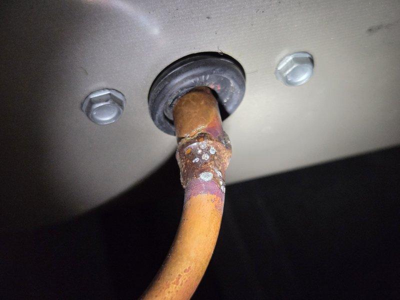 Responded to service call for 9-year-old air conditioning system experiencing frozen refrigerant lines and inadequate cooling performance. Upon inspection, discovered severe corrosion and deterioration on copper refrigerant lines at multiple connection points, including soldered joints and penetration points through exterior housing. The corrosion exhibited advanced oxidation with crusty white deposits and flaking material, indicating prolonged exposure to moisture and potential refrigerant leaks at compromised joints. Documented extensive damage to refrigerant piping system with photographic evidence showing rust, oxidation, and galvanic corrosion concentrated at connection points and soldered areas. System requires refrigerant line replacement due to compromised integrity of copper piping, which is causing recurring freeze-up conditions and reduced cooling capacity.