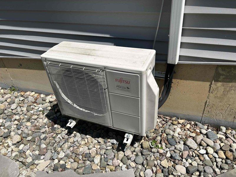Conducted estimate for mini-split system replacement in three-season room. Evaluated existing Fujitsu 12,000 BTU 1-to-1 ductless heat pump system experiencing refrigerant leak rendering unit inoperative. Documented current installation including outdoor condenser unit mounted on concrete pad and wall-mounted indoor air handler with refrigerant line set and electrical connections. Assessed installation site conditions on lakeside property with adequate clearances and proper drainage. Provided replacement options for failed system while noting main residence has separate central heating and cooling equipment.