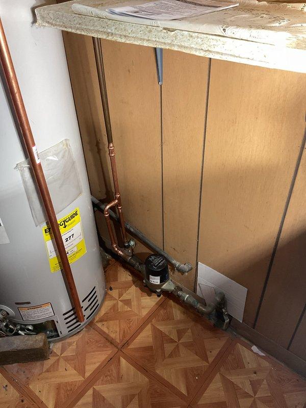 Installed black iron gas pipe to exterior of furnace cabinet and connected to existing gas line per code requirements. Replaced corroded and leaking copper water line at water meter with new supply piping. Extended TPR valve discharge piping to terminate within 6 inches of floor level to meet safety standards.