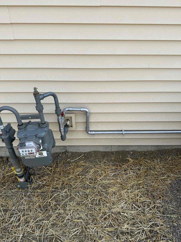 Installed natural gas line from existing residential gas meter to backup generator location. Ran approximately 8-10 feet of black iron pipe with appropriate fittings, elbows, and shut-off valve to supply fuel source for standby generator unit. Connected piping to meter assembly using code-compliant materials and secured all connections. Installation positioned along exterior foundation wall near existing HVAC equipment pad to maintain clean routing and accessibility for future service needs.