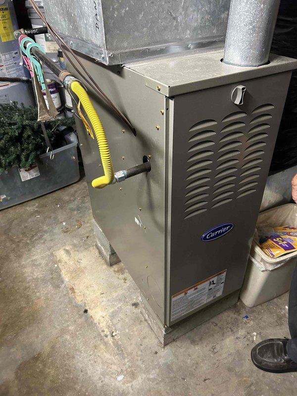 Conducted comprehensive assessment of existing HVAC system for replacement estimate. Evaluated outdoor Carrier condenser unit showing significant age and weathering, with deteriorated casing and worn components. Inspected refrigerant line routing along building exterior and electrical disconnect. Assessed indoor Carrier furnace installation in basement mechanical room, including existing ductwork configuration, gas line connections, and ventilation system. Documented current equipment specifications and installation conditions to provide accurate replacement recommendations for complete system upgrade.