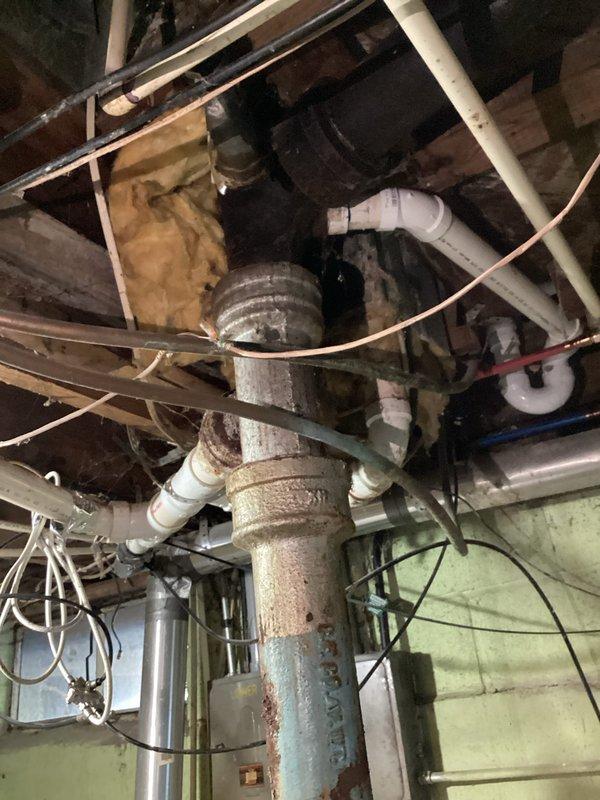 Responded to service call regarding unusual odor at rental property. Conducted thorough inspection of basement utility area and plumbing system to identify source of smell. Upon examination, discovered severely corroded vertical water supply pipe with extensive rust and surface degradation. Inspected all exposed plumbing including PVC drainage lines, vent pipes, and supply lines running through basement ceiling joists. Photographed corroded pipe and overall plumbing configuration for documentation. Confirmed odor was not sewer gas but likely related to deteriorated metal piping and potential moisture issues in the basement area. Recommended replacement of corroded pipe to prevent future leaks and eliminate odor source.