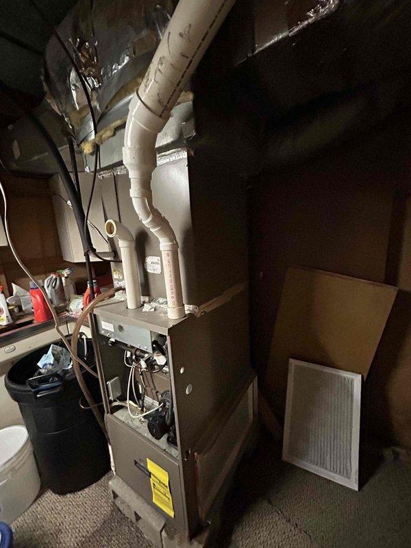 Conducted comprehensive HVAC system evaluation for replacement estimate on residential forced-air heating and cooling system. Existing air conditioning unit demonstrated inadequate cooling performance with documented history of repeated refrigerant additions over multiple years, indicating probable refrigerant leak in system. Assessed basement-mounted gas furnace with accessible service panel and inspected outdoor condensing unit housed in protective cage on concrete pad against brick exterior wall. Documented existing equipment configuration including PVC condensate drainage system, copper refrigerant line sets, and ductwork connections. Provided replacement options for complete HVAC system upgrade to address cooling deficiency and aging equipment.