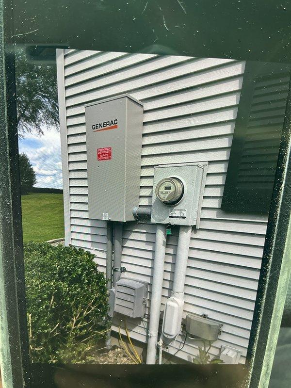 Completed installation of 22kW Generac propane-fueled standby generator with 200-amp automatic transfer switch (ATS) positioned approximately 20 feet from residence on pre-existing concrete pad adjacent to propane tank. Installation included oil warmer and battery warmer for cold-weather operation reliability. Ran conduit from generator to exterior-mounted ATS enclosure on home's siding, ensuring proper electrical connections between generator, transfer switch, and existing electrical service panel. Verified all electrical connections, tested ATS functionality, and confirmed generator startup and automatic transfer capabilities. System commissioned and operational, providing whole-house backup power protection.