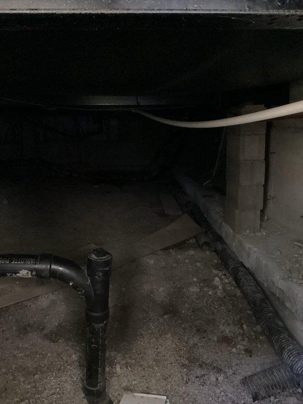 Responded to elevated water consumption complaint and conducted crawl space inspection beneath kitchen area. Located moisture accumulation on concrete floor in crawl space, consistent with reported water bill increase. Inspected exposed plumbing lines, floor joists, and foundation for active leaks or signs of water intrusion. Documented crawl space conditions including exposed ductwork, insulation, and plumbing infrastructure. Advised shutting off water supply to toilet exhibiting intermittent running to isolate potential contributing source of water waste. Noted secondary drainage concerns related to kitchen garbage disposal requiring plunging for proper function, which may indicate partial line obstruction. Photographed affected crawl space area showing moisture staining on concrete surfaces and overall utility space conditions for diagnostic reference.