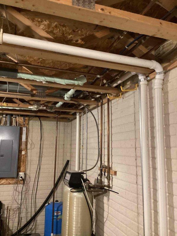 Conducted on-site assessment for relocating washer and dryer utilities from basement to second-floor bedroom directly above. Evaluated existing water supply lines, drainage piping, and gas line routing through floor joists and wall cavities. Inspected basement mechanical room containing water treatment equipment, electrical panel, and existing copper and PVC plumbing infrastructure. Assessed ceiling access points and determined optimal pathway for running new hot and cold water lines, waste drain, and gas line vertically through structure. Examined attic space and identified HVAC ductwork positioning to plan utility line routing that avoids conflicts with existing systems. Documented current plumbing configuration and identified multiple leak locations requiring repair. Photographed basement utility area showing exposed piping, water treatment systems, and structural layout. Provided comprehensive estimate for materials and labor required to relocate all necessary utilities while maint