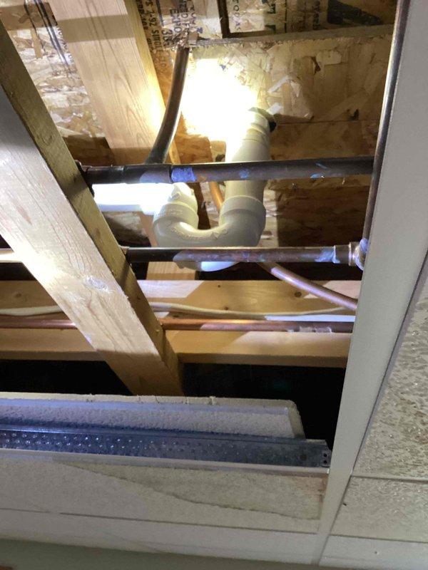 Conducted on-site assessment for relocating washer and dryer utilities from basement to second-floor bedroom directly above. Evaluated existing water supply lines, drainage piping, and gas line routing through floor joists and wall cavities. Inspected basement mechanical room containing water treatment equipment, electrical panel, and existing copper and PVC plumbing infrastructure. Assessed ceiling access points and determined optimal pathway for running new hot and cold water lines, waste drain, and gas line vertically through structure. Examined attic space and identified HVAC ductwork positioning to plan utility line routing that avoids conflicts with existing systems. Documented current plumbing configuration and identified multiple leak locations requiring repair. Photographed basement utility area showing exposed piping, water treatment systems, and structural layout. Provided comprehensive estimate for materials and labor required to relocate all necessary utilities while maint