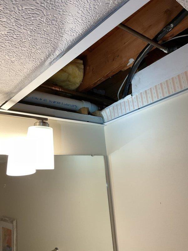 Responded to report of water damage visible in basement ceiling below main floor bathroom. Removed ceiling tile to access plumbing infrastructure and inspected PVC sewer line connections. Identified loose PVC joint connection requiring proper solvent welding to prevent future leakage. Applied PVC primer and cement to secure connection, ensuring watertight seal per plumbing code standards.