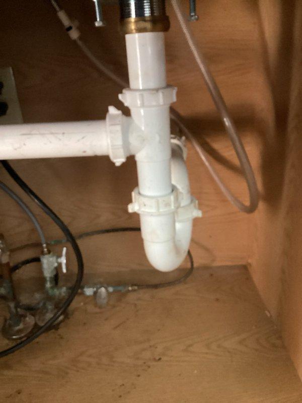 Responded to kitchen sink drainage issue where water backed up during dishwasher operation. Upon inspection, discovered clogged drain line and non-functional garbage disposal unit contributing to poor drainage. Cleared obstruction from drain system and assessed existing plumbing configuration, which included aging corroded metal components and PVC trap assembly. Discussed option of removing garbage disposal unit to prevent future drainage problems, as disposal appeared to be primary source of blockage and was no longer operational.