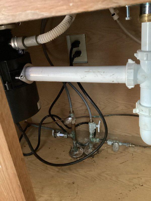 Responded to kitchen sink drainage issue where water backed up during dishwasher operation. Upon inspection, discovered clogged drain line and non-functional garbage disposal unit contributing to poor drainage. Cleared obstruction from drain system and assessed existing plumbing configuration, which included aging corroded metal components and PVC trap assembly. Discussed option of removing garbage disposal unit to prevent future drainage problems, as disposal appeared to be primary source of blockage and was no longer operational.