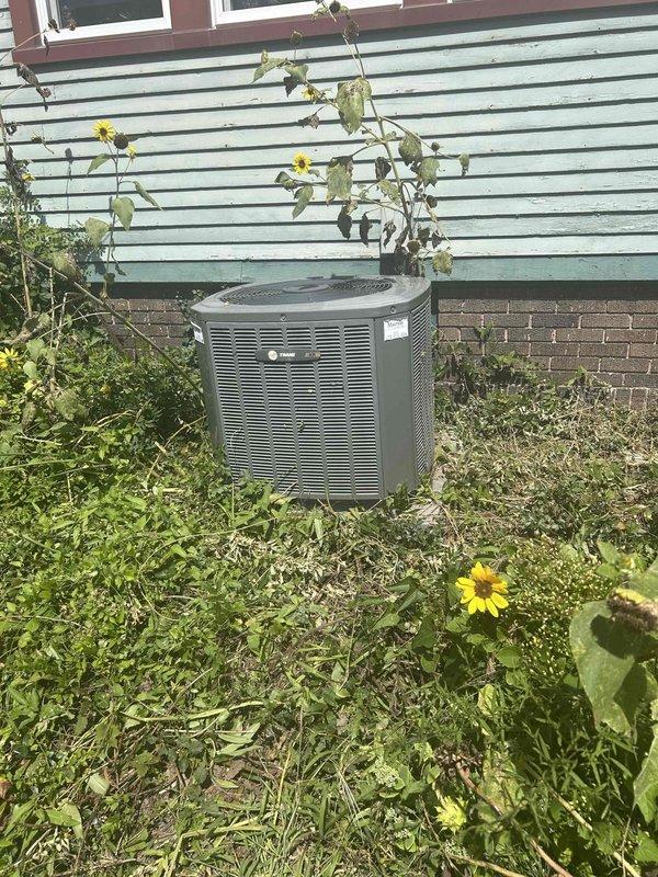 Performed site evaluation of existing Trane outdoor condensing unit and indoor HVAC components to provide replacement estimate. Documented current equipment dimensions and condition, noting the outdoor unit's placement on concrete pad with adequate clearance for service access. Assessed indoor system components including ductwork connections and verified measurements for proper equipment sizing recommendations.