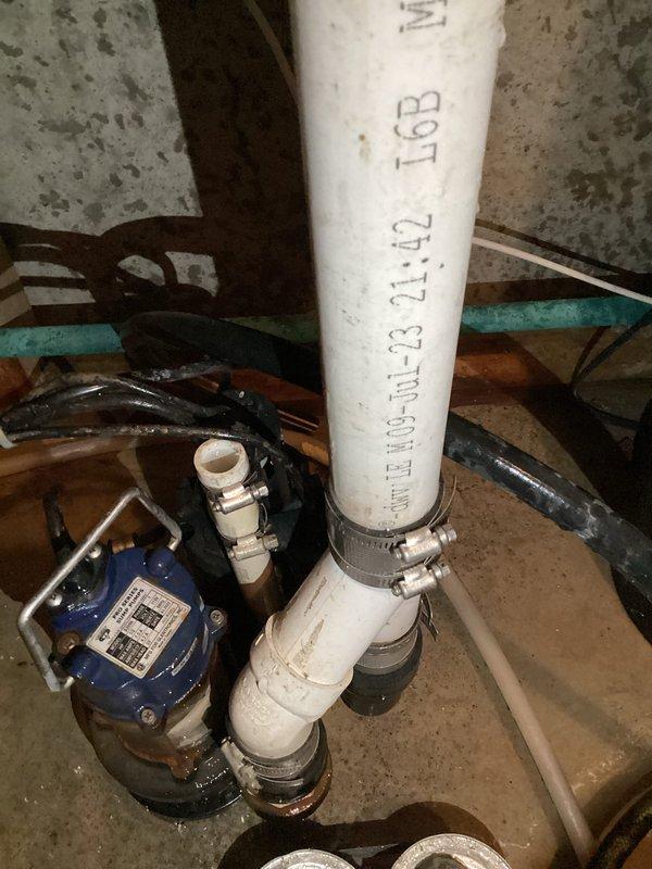 Responded to emergency service call for non-operational sump pump causing basement flooding. Upon arrival, assessed the failed pump system and standing water conditions. Removed and replaced defective sump pump unit with new blue submersible pump assembly. Installed pump in existing sump basin and connected discharge piping using white PVC pipe with proper metal hose clamps at all connection points. Verified all mechanical fittings were secure and tested pump operation to ensure proper activation and water discharge. Documented installation with photographs showing completed pump assembly, piping configuration, and secure mounting. Contacted property management upon completion to confirm system restoration and proper operation.