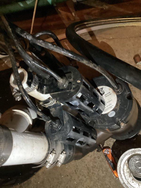 Responded to emergency service call for non-operational sump pump causing basement flooding. Upon arrival, assessed the failed pump system and standing water conditions. Removed and replaced defective sump pump unit with new blue submersible pump assembly. Installed pump in existing sump basin and connected discharge piping using white PVC pipe with proper metal hose clamps at all connection points. Verified all mechanical fittings were secure and tested pump operation to ensure proper activation and water discharge. Documented installation with photographs showing completed pump assembly, piping configuration, and secure mounting. Contacted property management upon completion to confirm system restoration and proper operation.