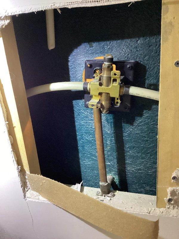 Responded to upstairs shower leak complaint. Accessed shower valve assembly through wall opening to address leaking fixture that customer was unable to disassemble. Removed corroded trim cover and escutcheon displaying significant oxidation and mineral buildup. Replaced internal valve cartridge components with customer-supplied parts. Reassembled fixture with proper sealing to prevent further water intrusion into wall cavity.