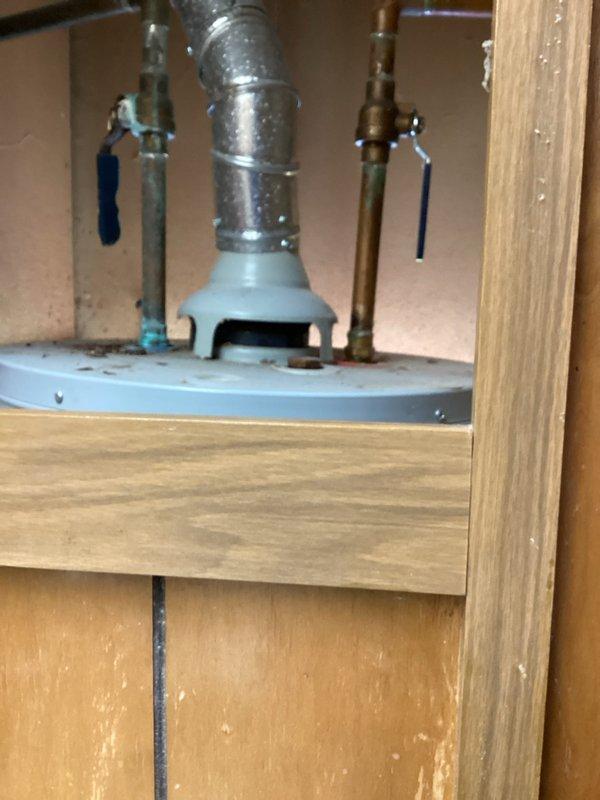 Provided estimate for gas water heater replacement in mobile home. Unit is currently accessed through exterior wall opening with visible deterioration to wooden frame requiring attention during installation. Assessed existing installation configuration including gas supply lines, venting requirements, and exterior access panel specifications unique to mobile home applications.