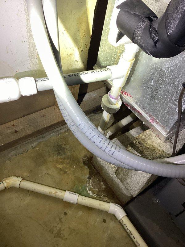 Responded to water leak at piping connection on water furnace in basement utility area. Upon inspection, identified slow drip at PVC condensate drain line assembly near furnace unit. Examined white PVC piping configuration including multiple 90-degree elbows, threaded couplings, and drain collection point with black grate cover. Assessed connection points and fittings for proper sealing and potential failure points. Noted moisture staining on concrete floor beneath affected area indicating previous leaking. Tightened connections at piping joints and verified all PVC fittings were properly secured. Inspected foam insulation on adjacent HVAC components for water damage. Tested system operation and monitored for active leaking. Confirmed leak was temporarily resolved and provided recommendations for ongoing monitoring. Documented equipment condition and piping assembly with photographs for service records.