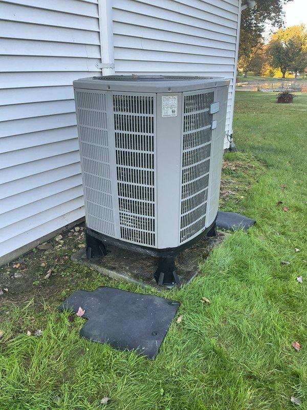 Completed follow-up service call to install stabilizing support pads beneath heat pump condenser unit. Positioned and leveled black composite equipment pads on ground surface to provide proper foundation and prevent settling. Unit now sits securely on upgraded pad system, ensuring stable operation and proper drainage around equipment.