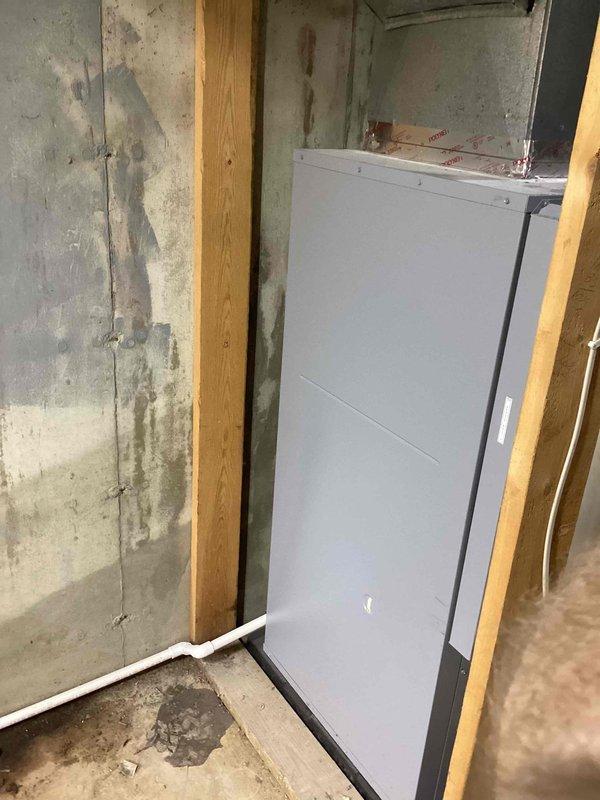 Installed a vertical geothermal water-source heat pump in the basement, connecting it to the supply and return ductwork with sealed, foil-taped transitions and mounting it on an isolation pad. Piped the ground loop through a manifold with isolation valves and insulated loop piping, with a filter/canister and condensate drain piping, then wired the line-voltage and control circuits, including the wall thermostat. Verified connections and completed system setup for operation.