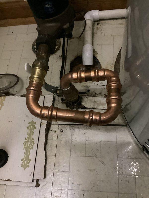 Installed a new 50-gallon gas tank-style water heater on the main floor, connecting copper supply lines with press-fit fittings, a brass ball valve on the cold inlet, and a galvanized flue vented through the draft hood. Replaced the home's main shutoff valve with a new brass valve and copper piping, restoring reliable whole-house water isolation. Verified connections are secure and leak-free, with no visible rust or moisture at the completed installation.