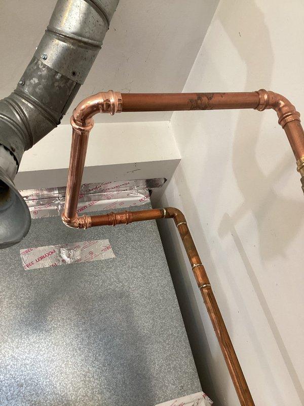 Replaced the tanked water heater and its magnesium anode rod to address recurring debris clogging drains and aerators that began after the prior unit's installation. After removing the old unit, flushed the domestic water lines with fresh water to clear remaining sediment, then verified clear, steady flow at the bathroom faucet with no leaks present at the copper supply connections.