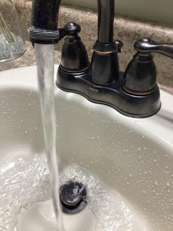 Replaced the tanked water heater and its magnesium anode rod to address recurring debris clogging drains and aerators that began after the prior unit's installation. After removing the old unit, flushed the domestic water lines with fresh water to clear remaining sediment, then verified clear, steady flow at the bathroom faucet with no leaks present at the copper supply connections.