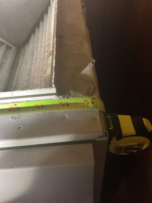 Performed an on-site evaluation for a full HVAC system replacement, including measuring the air handler cabinet and filter section dimensions and inspecting the existing pleated filter and insulated panel, which showed dust accumulation and frayed insulation at the edges. Also took clearance measurements of the surrounding floor space, which includes vinyl tile and a rough concrete surface, to confirm equipment fit and installation requirements for the new system quote.