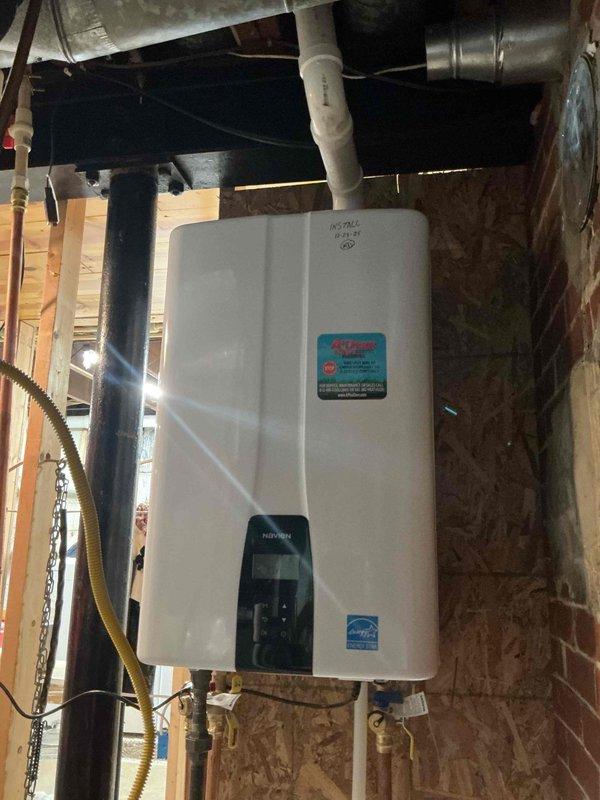 Successfully installed a new tankless water heater in unfinished basement area. Mounted unit on plywood wall with proper connections including copper pipes, PVC venting, and yellow gas line. Completed all necessary utility connections and verified proper operation of the Energy Star certified unit.