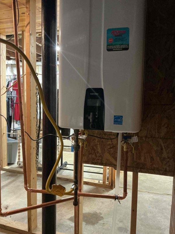 Successfully installed a new tankless water heater in unfinished basement area. Mounted unit on plywood wall with proper connections including copper pipes, PVC venting, and yellow gas line. Completed all necessary utility connections and verified proper operation of the Energy Star certified unit.