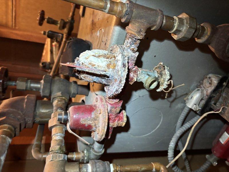 Diagnosed and replaced failed circulator pump motor on 20+ year old boiler system that was preventing hot water distribution through the heating system. Visual inspection revealed extensive corrosion and mineral buildup on multiple valves and pipe connections throughout the system. Recommended customer consider system replacement due to advanced deterioration and multiple components nearing end of service life.