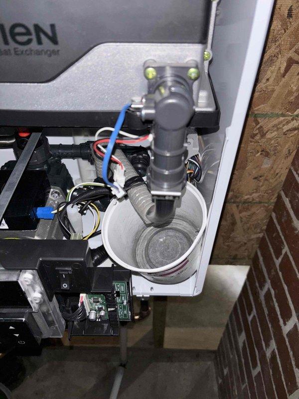 Inspected water heater system following complaint of leakage. Verified customer report of tank leaking in two distinct areas as noted by Brent. Documented issues with detailed photographs of the heat exchanger system, condensate drain assembly, and associated plumbing components. Observed PVC drain pipe configuration and electrical connections to determine proper remediation steps for the leaking tank.