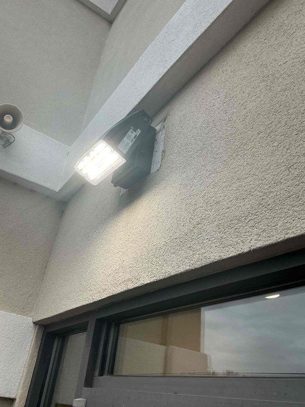 Conducted follow-up inspection of exterior lighting at commercial property. Verified proper functioning of entry door illumination and wall-mounted LED floodlight. All lighting fixtures operating as expected with appropriate coverage of entrance and building perimeter.