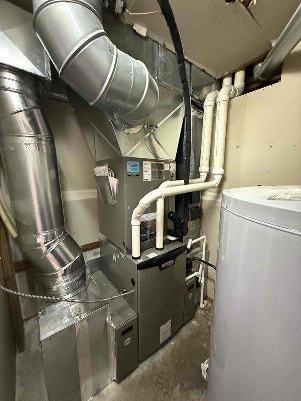 Completed installation of a Green5T 18S 99UP HVAC system at customer's residence. Indoor work included installation of furnace unit with complete ductwork system and appropriate PVC venting. Outdoor unit was properly mounted on concrete pad with electrical connections secured to the home's exterior, though some ground erosion was noted around the pad area.