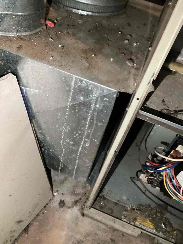 Conducted on-site assessment of aging furnace unit in basement utility room. System shows significant dust accumulation and wear on ductwork components. Noted exposed wiring on control unit with visible red, blue, and yellow wires. Prepared replacement estimate for customer to upgrade existing HVAC system with new energy-efficient equipment.