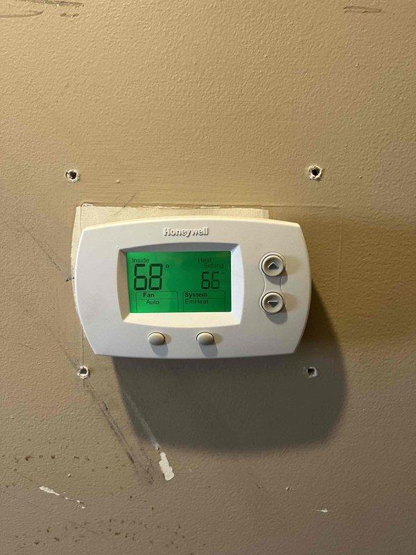 Performed annual Gold Level maintenance on customer's 5-year-old Goodman HVAC system. Inspected outdoor condenser unit and verified proper operation. Checked Honeywell thermostat functionality, confirming emergency heat mode operation with current temperature reading of 68°F against set point of 66°F and auto fan setting.